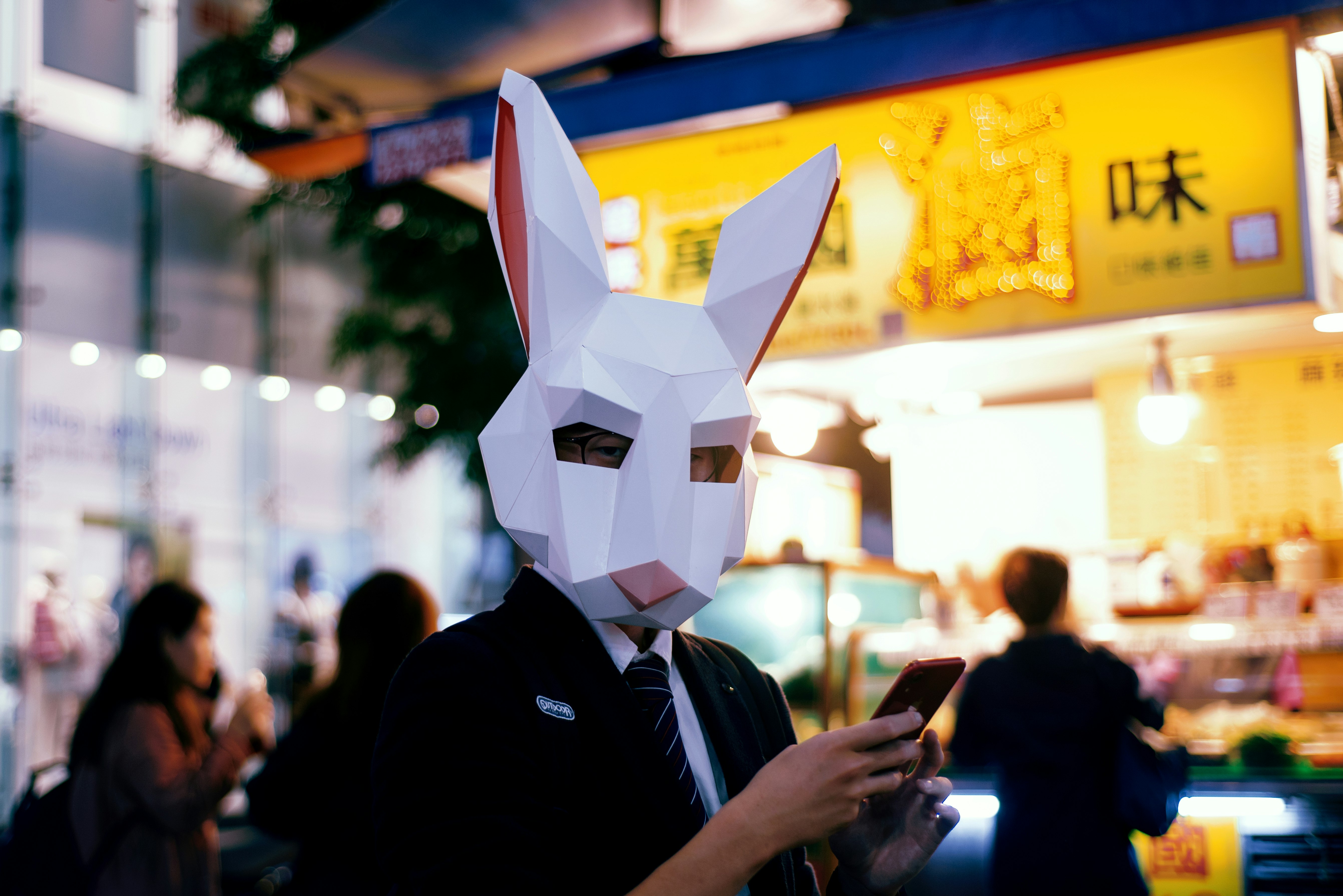 man in black jacket holding white paper mask